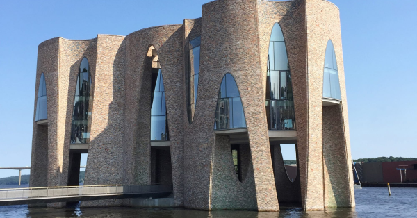 Construção moderna de arquitetura contemporânea sobre a água, com destaque para o design criativo e sustentável.
